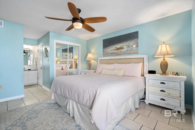 tiled bedroom featuring a textured ceiling, a ceiling fan, ensuite bathroom, baseboards, and a closet