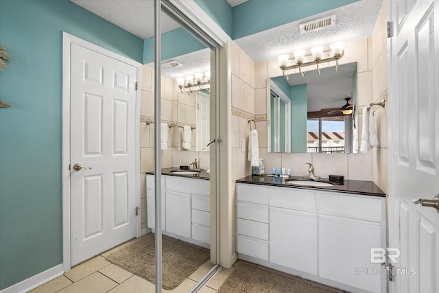 full bathroom featuring vanity, ceiling fan, a textured ceiling, and tile patterned floors