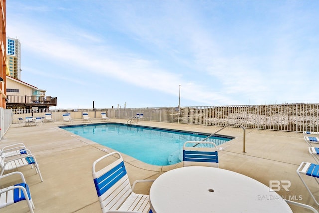 community pool with fence and a patio area