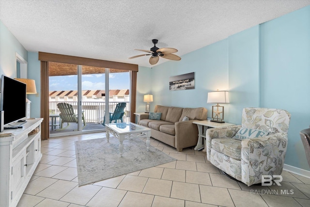 living room with a ceiling fan, a textured ceiling, and light tile patterned floors