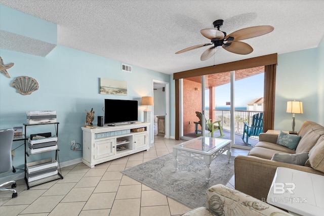 living room featuring ceiling fan, light tile patterned flooring, a textured ceiling, and baseboards
