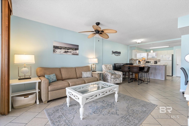 living area featuring light tile patterned flooring, a ceiling fan, and a textured ceiling