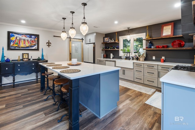 kitchen with dark wood-type flooring, sink, pendant lighting, white refrigerator, and a center island