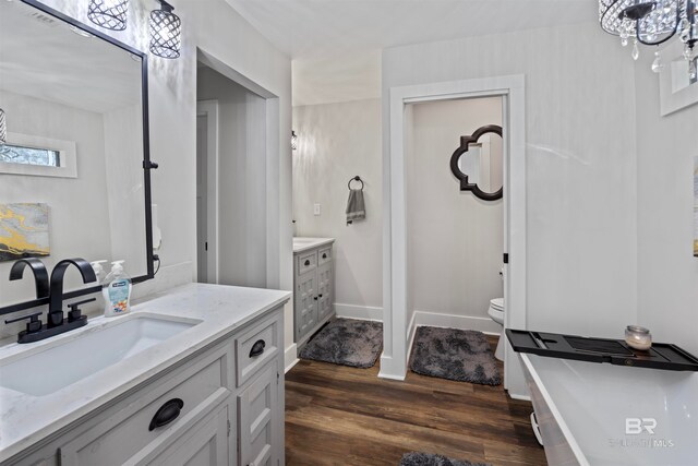 bathroom featuring hardwood / wood-style floors, vanity, toilet, and an inviting chandelier