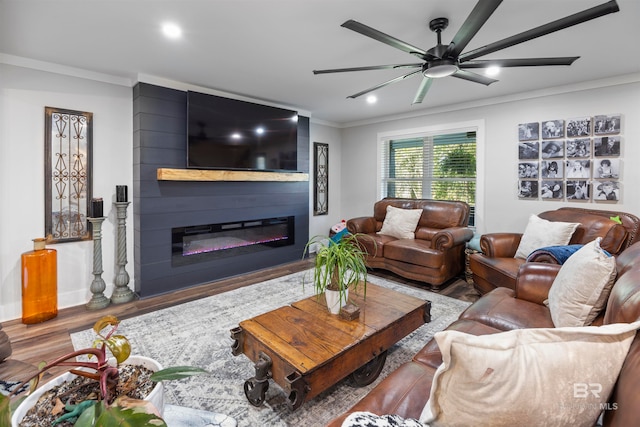 living room with hardwood / wood-style floors, ceiling fan, crown molding, and a fireplace