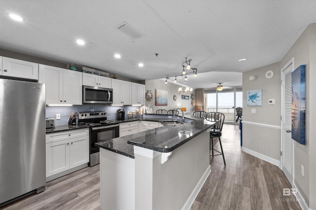 kitchen featuring light hardwood / wood-style flooring, a kitchen breakfast bar, appliances with stainless steel finishes, and white cabinets