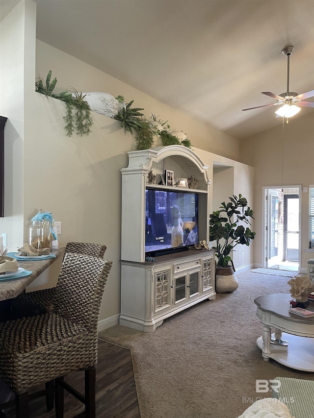 carpeted living room with a ceiling fan, vaulted ceiling, and baseboards