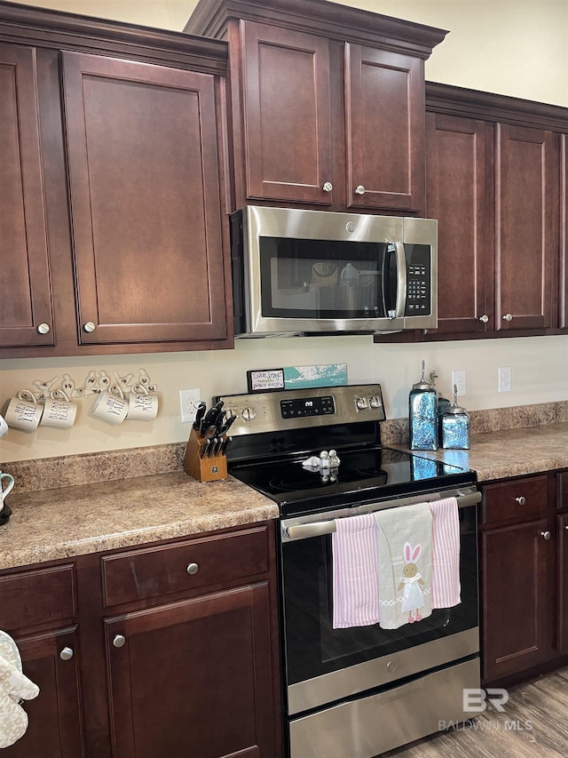 kitchen with dark brown cabinetry, appliances with stainless steel finishes, light countertops, and wood finished floors