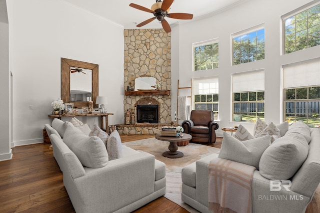 living room with a fireplace, dark hardwood / wood-style flooring, a high ceiling, ceiling fan, and crown molding