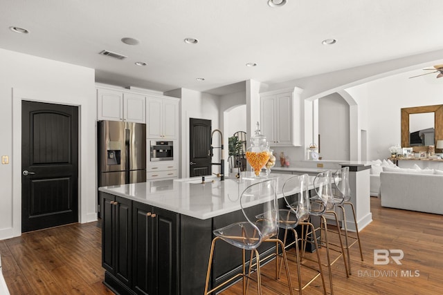 kitchen featuring white cabinetry, stainless steel appliances, dark hardwood / wood-style flooring, and an island with sink