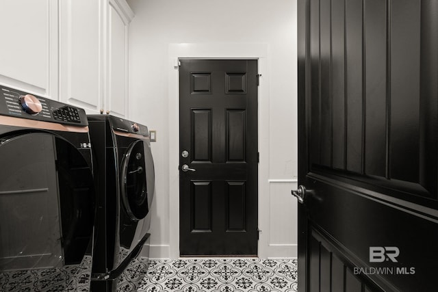 washroom with light tile patterned floors, washing machine and dryer, and cabinets