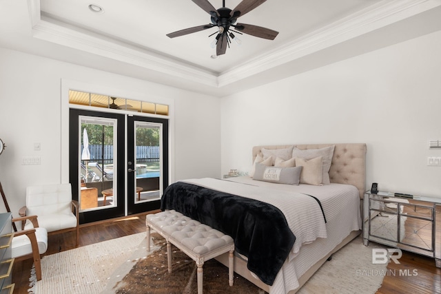 bedroom with hardwood / wood-style flooring, a tray ceiling, crown molding, and access to outside