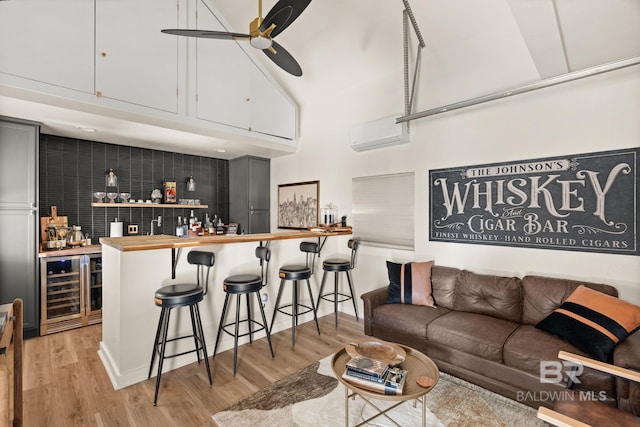 bar featuring butcher block countertops, a wall mounted AC, wine cooler, ceiling fan, and light hardwood / wood-style floors