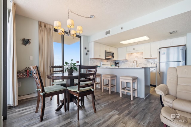 24400 Perdido Beach Blvd Unit 701, Orange Beach, AL 36561 - dining area featuring dark wood-style flooring, visible vents, an inviting chandelier, and a textured ceiling