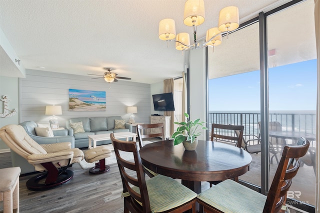 24400 Perdido Beach Blvd Unit 701, Orange Beach, AL 36561 - dining room featuring a textured ceiling, wood finished floors, ceiling fan with notable chandelier, wood walls, and expansive windows