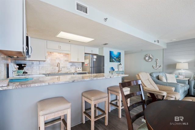 24400 Perdido Beach Blvd Unit 701, Orange Beach, AL 36561 - kitchen with light stone counters, a peninsula, open floor plan, visible vents, and appliances with stainless steel finishes