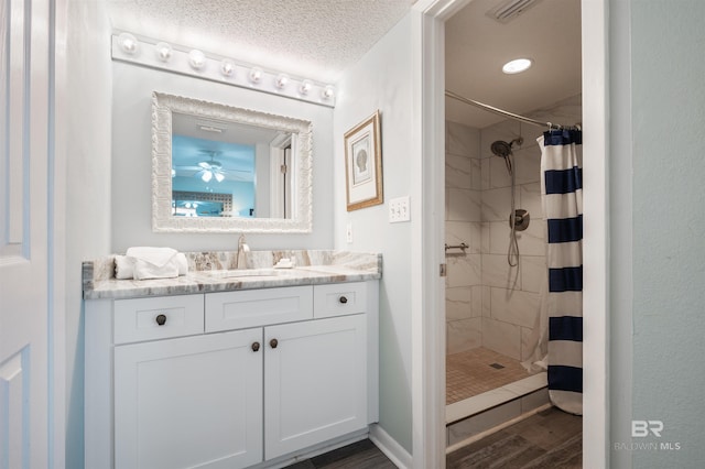 24400 Perdido Beach Blvd Unit 701, Orange Beach, AL 36561 - bathroom featuring a tile shower, a textured ceiling, vanity, visible vents, and wood finished floors