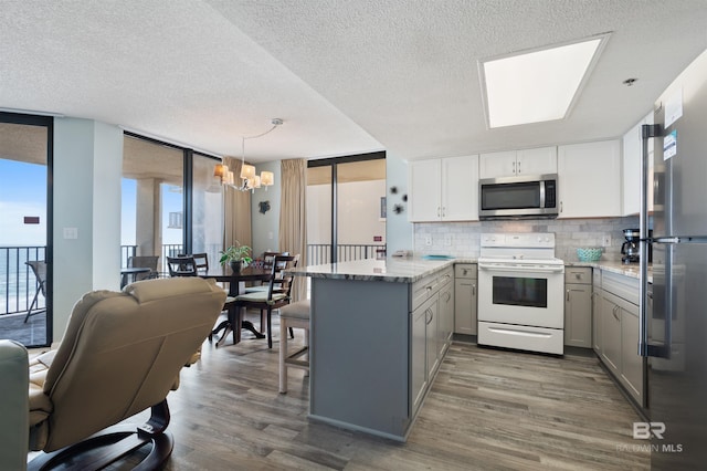 24400 Perdido Beach Blvd Unit 701, Orange Beach, AL 36561 - kitchen featuring a notable chandelier, a peninsula, stainless steel appliances, gray cabinets, and expansive windows