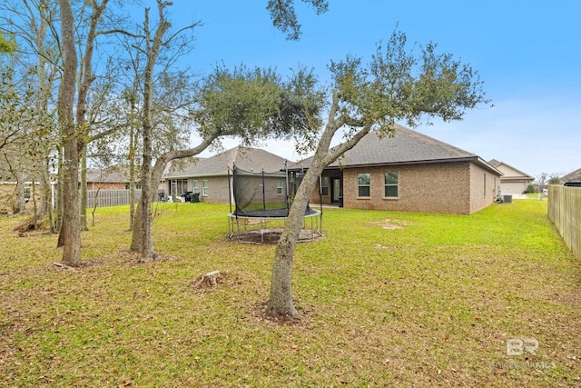 9393 Impala Dr, Foley, AL 36535 - back of property with brick siding, a trampoline, a lawn, and fence