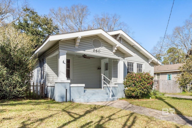 bungalow-style home featuring a ceiling fan, a front lawn, and fence