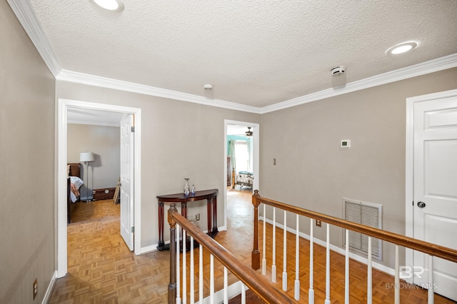 hall with ornamental molding, a textured ceiling, and light parquet floors