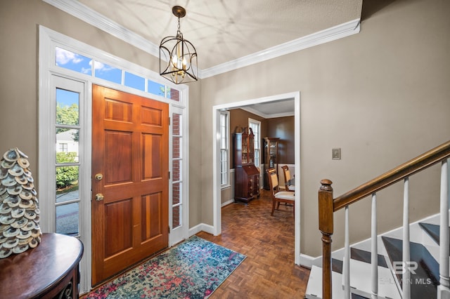 foyer entrance with ornamental molding, dark parquet floors, a textured ceiling, and an inviting chandelier