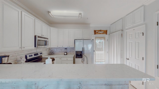 kitchen with tasteful backsplash, appliances with stainless steel finishes, kitchen peninsula, and white cabinets