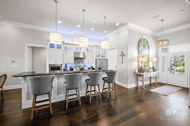 kitchen with a kitchen breakfast bar, white cabinetry, hanging light fixtures, and appliances with stainless steel finishes