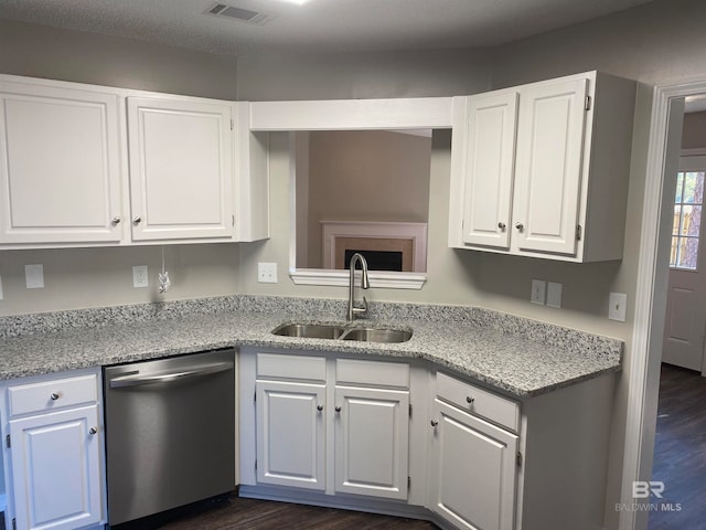 kitchen featuring dark wood-type flooring, sink, stainless steel dishwasher, white cabinetry, and light stone counters