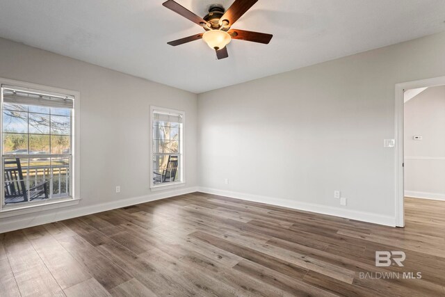 unfurnished room with a ceiling fan, baseboards, and wood finished floors