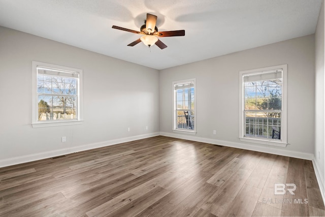 empty room featuring a ceiling fan, dark wood-style flooring, and baseboards