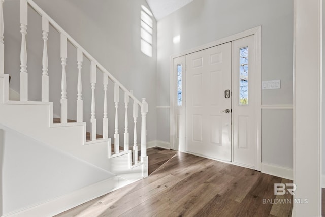 entryway featuring baseboards, stairway, and wood finished floors