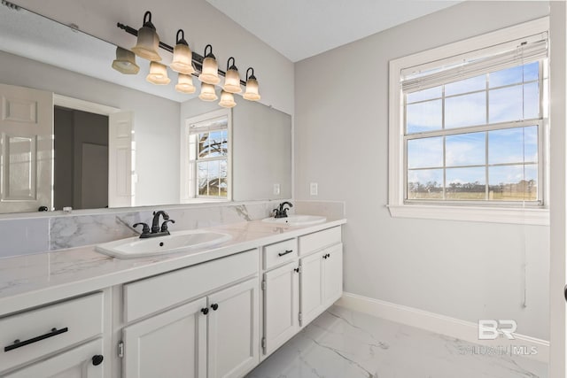 full bath featuring marble finish floor, a sink, baseboards, and double vanity