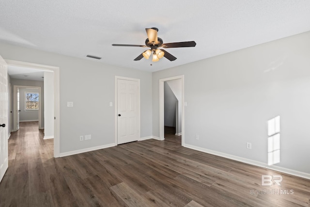 interior space with ceiling fan, dark wood-type flooring, visible vents, and baseboards