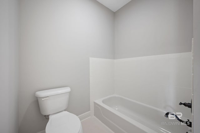 bathroom featuring a washtub, baseboards, and toilet