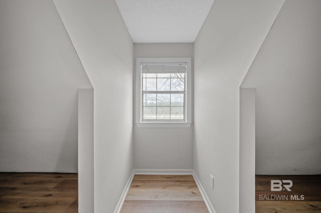 additional living space with a textured ceiling, wood finished floors, and baseboards