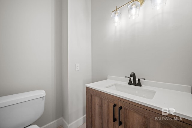 bathroom featuring toilet, baseboards, and vanity