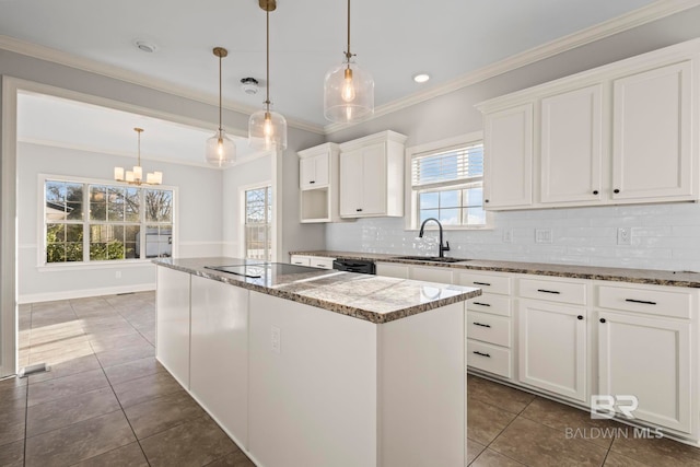 kitchen with stone countertops, a sink, a center island, decorative backsplash, and black appliances