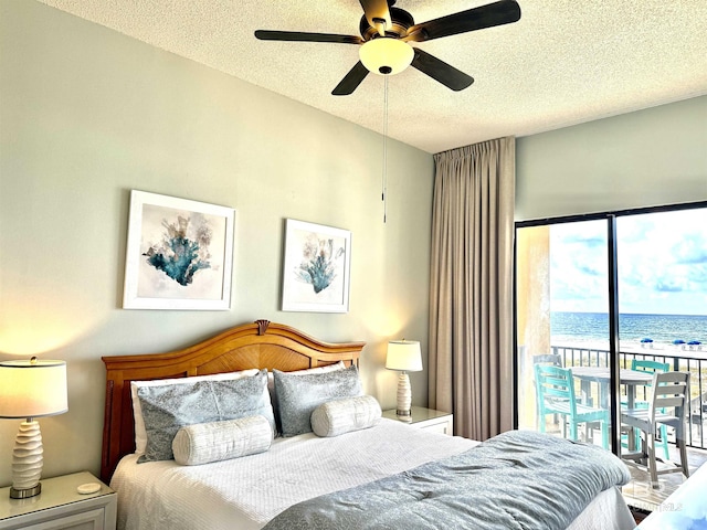 bedroom featuring a textured ceiling, ceiling fan, a water view, and access to outside