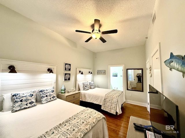 bedroom with a textured ceiling, visible vents, lofted ceiling, and dark wood-type flooring