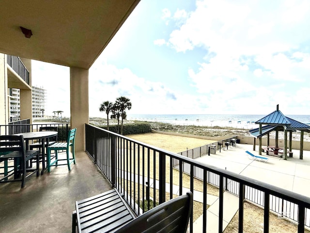 balcony featuring a view of the beach and a water view