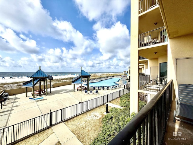 balcony with a patio, a beach view, and a water view