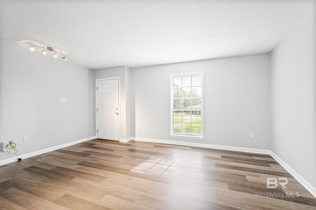 spare room with light hardwood / wood-style floors and a textured ceiling