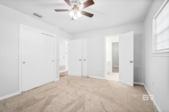 unfurnished bedroom featuring ceiling fan, ensuite bath, and carpet