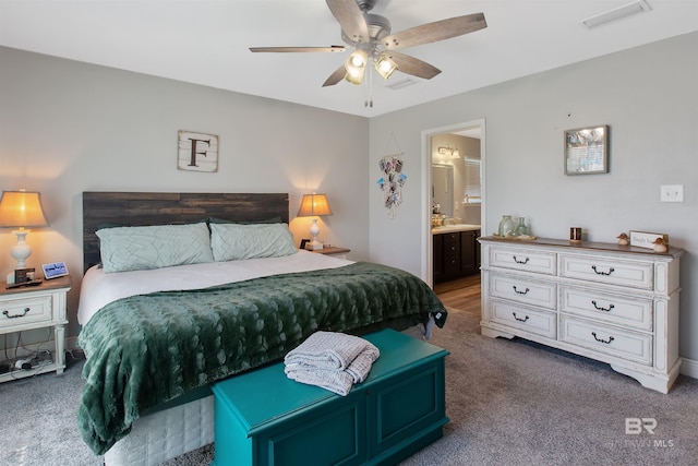 carpeted bedroom with ensuite bath and ceiling fan