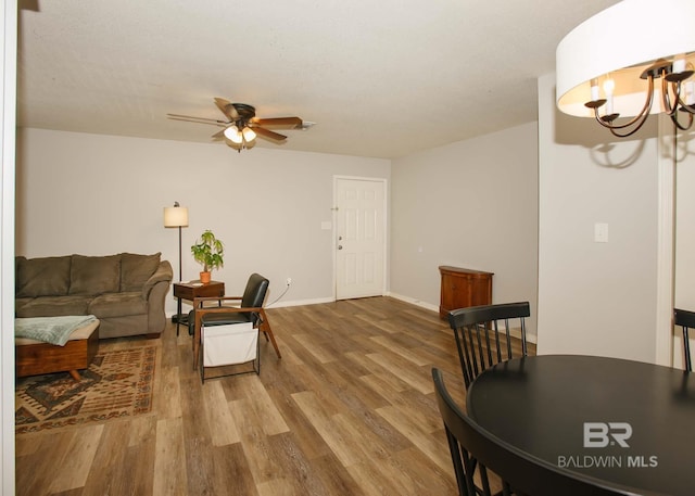 living room featuring ceiling fan with notable chandelier and hardwood / wood-style flooring