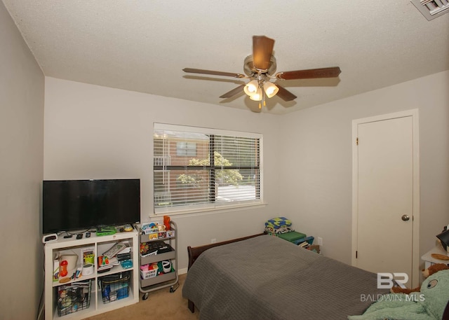 carpeted bedroom with ceiling fan and a textured ceiling