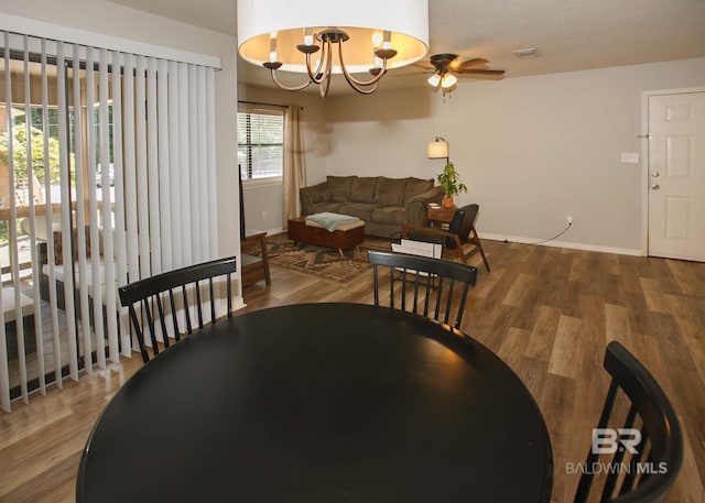 dining space featuring hardwood / wood-style floors and ceiling fan with notable chandelier