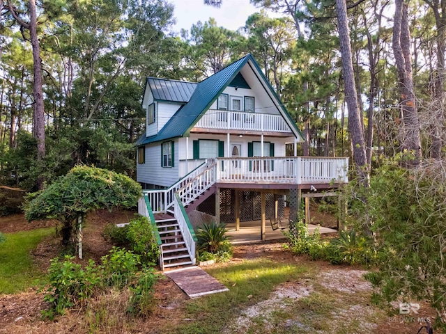 view of front of house with stairs, metal roof, and a balcony