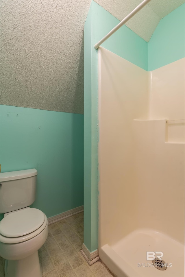 bathroom featuring lofted ceiling, a stall shower, a textured ceiling, and toilet